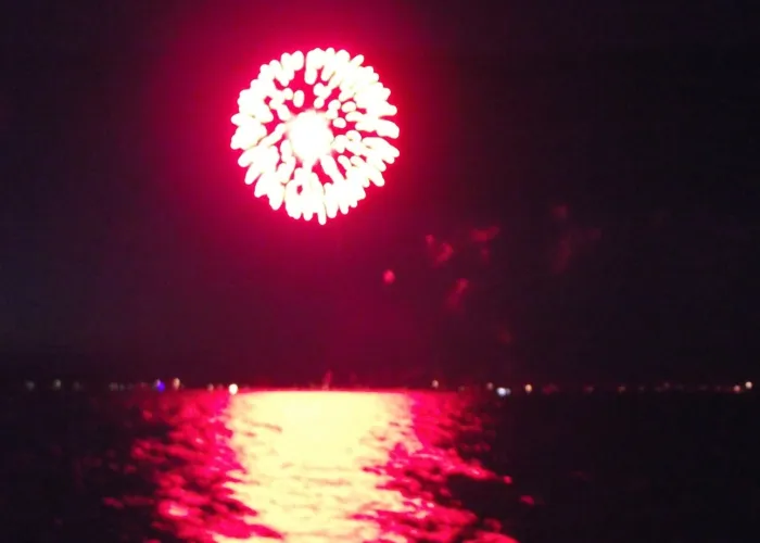 Fireworks exploding over lake, red tinge to photo